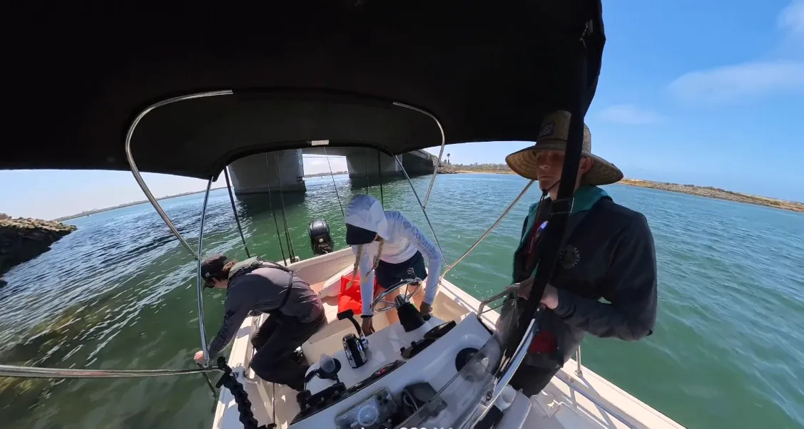 Crew rigging aboard GrayLITE under a harbor bridge